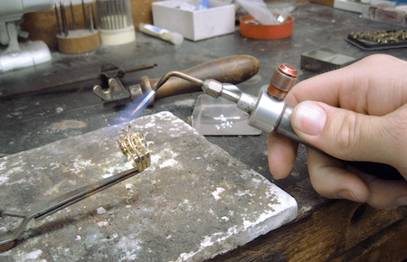 Master jeweler repairing ring on jewelers bench